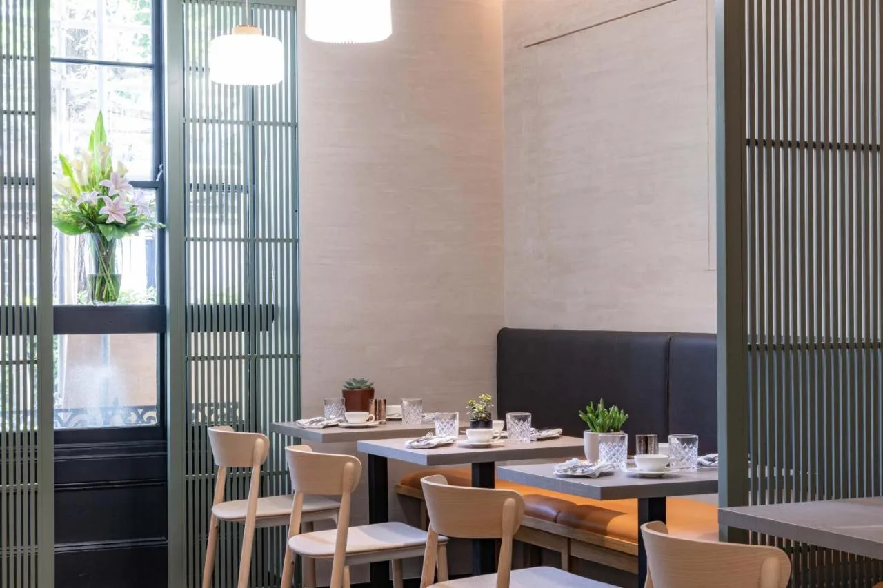 a dining room with tables and chairs and a window at La Suite West - Hyde Park in London